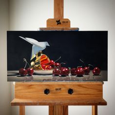 an easel holding a painting with cherries on it