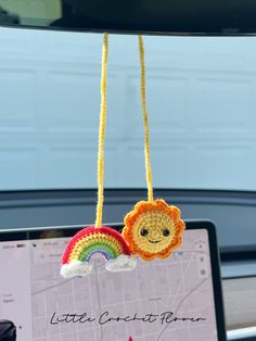 a laptop computer sitting on top of a desk with crocheted decorations hanging from it