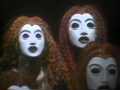 three white masks with red hair and black eyes are shown in front of a dark background