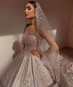 a woman in a wedding dress with a veil on her head, standing against a wall