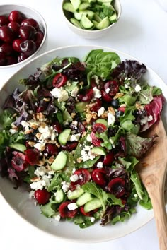 a salad with cherries, cucumbers and feta cheese is on a white plate