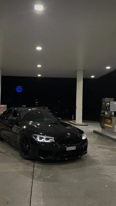 a black car parked in front of a gas station with its lights on at night