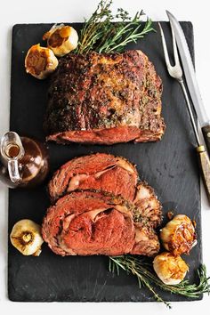 two meats on a cutting board next to garlic and an herb garnish