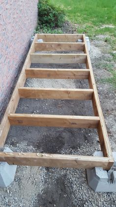 a wooden bed frame sitting next to a brick wall