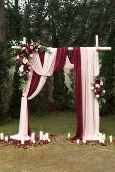 an outdoor wedding ceremony setup with candles and flowers on the aisle, decorated with red and white draping