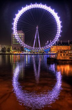 the london eye is lit up at night with bright lights on it's sides