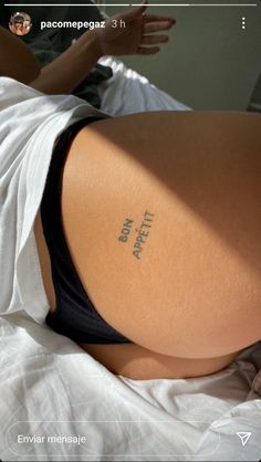 a woman laying in bed with her back turned to the camera and writing on her stomach