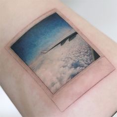 an airplane is flying over the clouds in this tattoo design on someone's arm