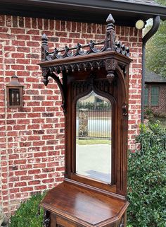 an old fashioned wooden mirror sitting on top of a table in front of a brick building