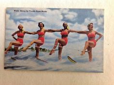 four women in swimsuits on skis are posing for the camera with their arms stretched out