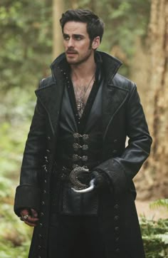 a man dressed in black standing in the woods