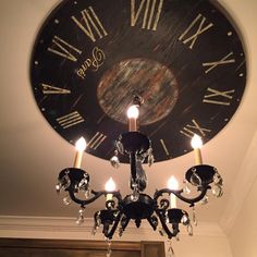 a chandelier hanging from the ceiling in front of a clock