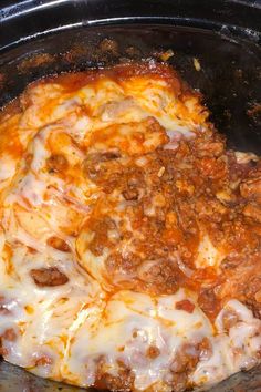 a close up of a pizza in a crock pot with cheese and meat on top