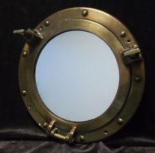 an old brass porthole mirror on a black background