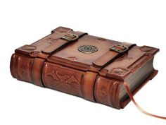 a brown leather book with an intricate design on the front and sides, tied to a cord