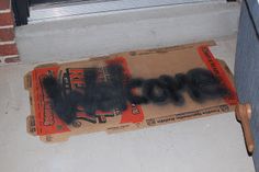 a cardboard box that has some type of graffiti on it, sitting in front of a window