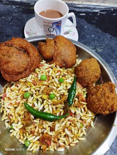 a plate full of rice and fried food next to a cup of coffee