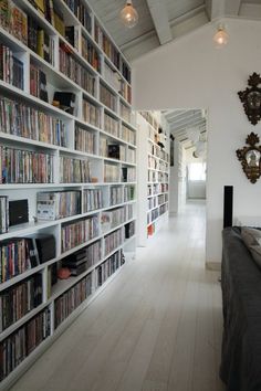 a room filled with lots of books on shelves next to a wall full of movies