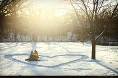 two people are sitting in the snow with their backs to each other and one person is hugging