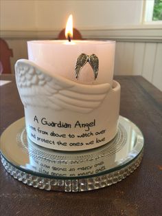 a white candle sitting on top of a glass plate next to an angel's wing