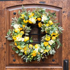 a wreath with lemons and white flowers is hanging on the front door to welcome guests