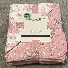 the pink and white floral bedding set is folded up on top of the carpet