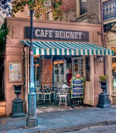 the outside of a cafe with tables and chairs on the sidewalk in front of it