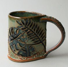 a ceramic coffee mug with an intricate design on it's side and inside rim