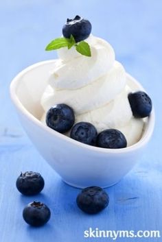 blueberries and ice cream in a white bowl on a blue background with the words, yogurt