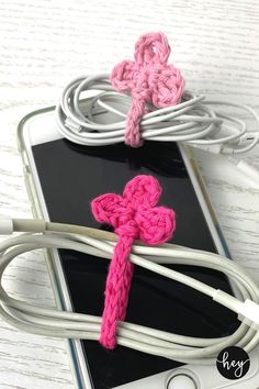 two crocheted pink and white crosses connected to an iphone charger on a table