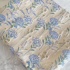 a blue and white flowered bed spread on top of a tablecloth covered surface