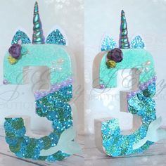 the letters are decorated with blue glitter and unicorn horns