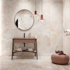 a bathroom with marble walls and flooring has a round mirror on the wall above it