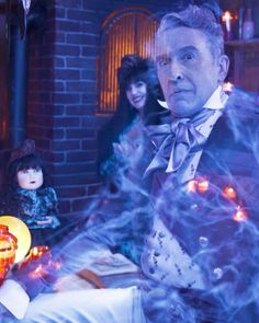 a man in a suit and bow tie standing next to a table with halloween decorations on it