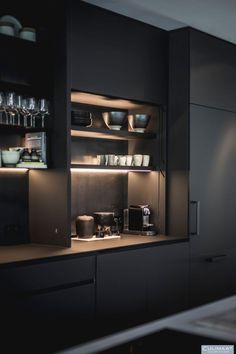 a kitchen with black cabinets and shelves filled with dishes