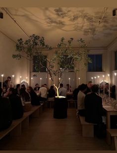 a group of people sitting at tables in a room with candles on the walls and windows