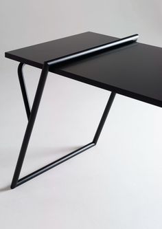 a black table with a pen on it and a white wall in the back ground