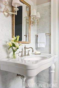 a white sink sitting under a bathroom mirror next to a wall mounted faucet