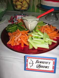 carrots, celery and other vegetables on a red plate with a small bowl of ranch dressing