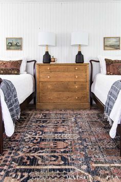 two twin beds in a bedroom next to a dresser with lamps on top of it