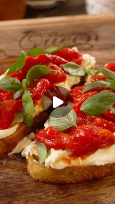 two pieces of bread with tomato sauce and basil on top, sitting on a cutting board