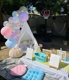 a tent with balloons and other items on the ground in front of an outdoor table