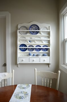 a wooden table with plates on it and a white china cabinet in the corner behind it