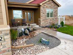 a house with rocks and gravel in front of it, next to a lawn area