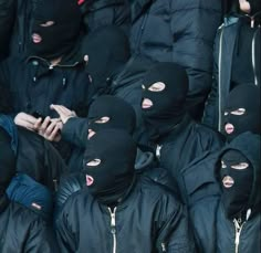 a group of masked people standing next to each other with their faces covered by black cloths