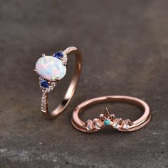 an opal and diamond ring set on a stone surface with the opal in between