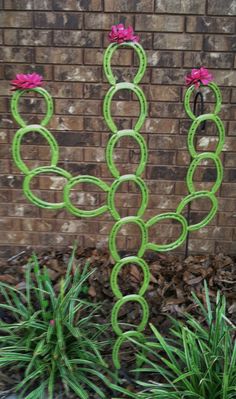 a sculpture made out of green circles and pink flowers in front of a brick wall