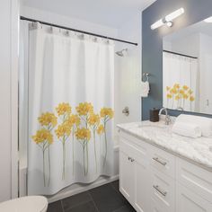 a white bathroom with yellow flowers on the shower curtain