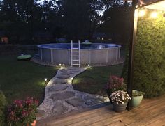 a backyard with a lit up pool and steps leading to the deck area at night