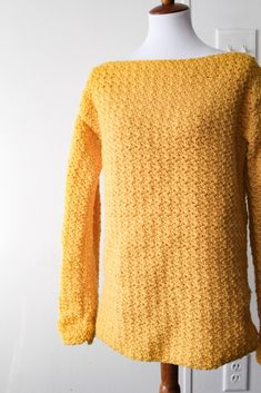 a yellow sweater sitting on top of a white mannequin